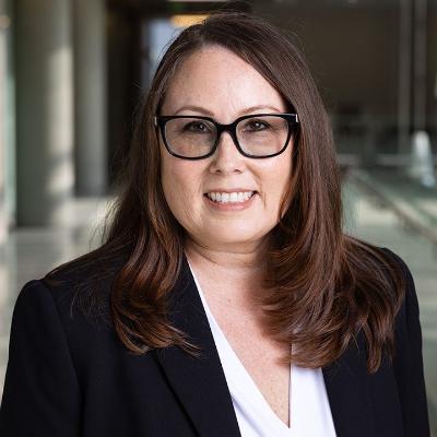 headshot portrait of woman with glasses standing in hallway